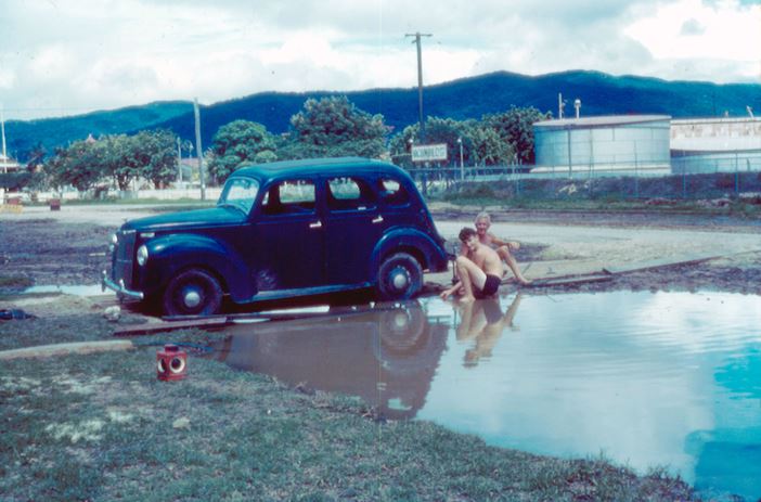 Our old prefect bogged in the sewerage trench outside the house. This was taken at Christmas time 1961 (I think), as that is my dad, George Wood, and my cousin, Jim Hoare trying to get the car out of the mud.